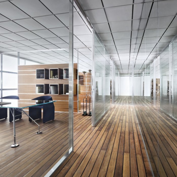 Pareti divisorie vetrate con profili in alluminio tra open space e sala riunioni in un ufficio moderno